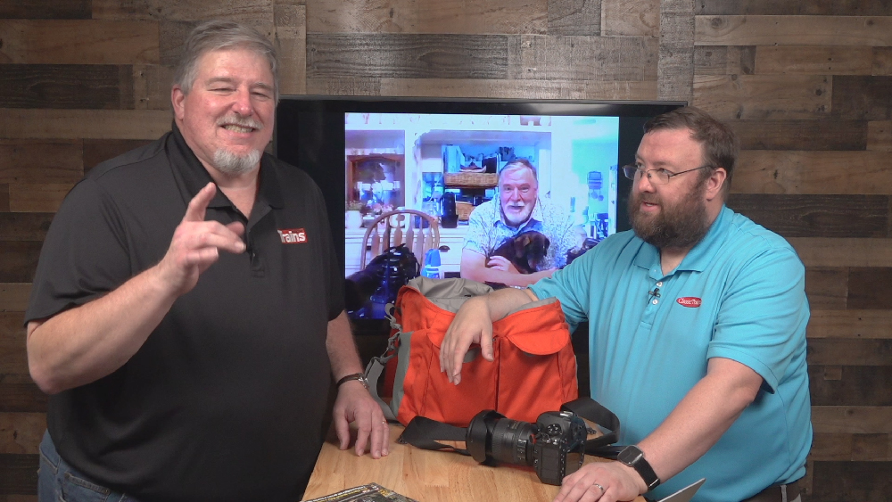 Two men in a TV studio joined by on a TV screen for an interview. Trains LIVE — what's in the bag?