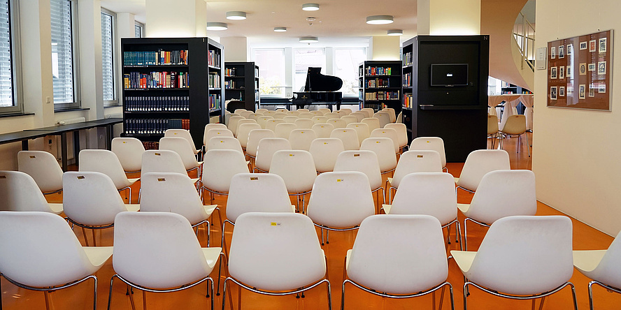 Bibliothek mit mehreren Stuhlreihen und einem Klavier