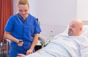 Ein Gesundheitspfleger steht am Bett eines Patienten