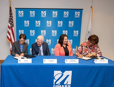 UMass Lowell Chancellor Julie Chen, left, and SAIC CEO Toni Townes-Whitley, far right, sign a partnership to create the UMass Lowell Cyber Center. Looking on are UMass President Marty Meehan and Massachusetts Lt. Gov. Kim Driscoll.