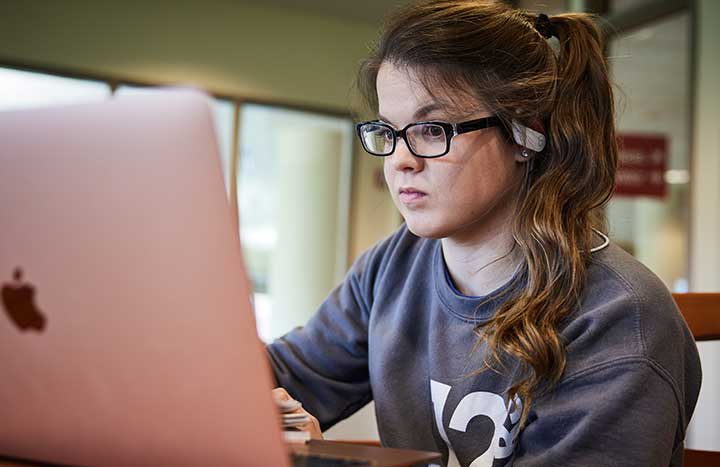 Student seated at table with laptop