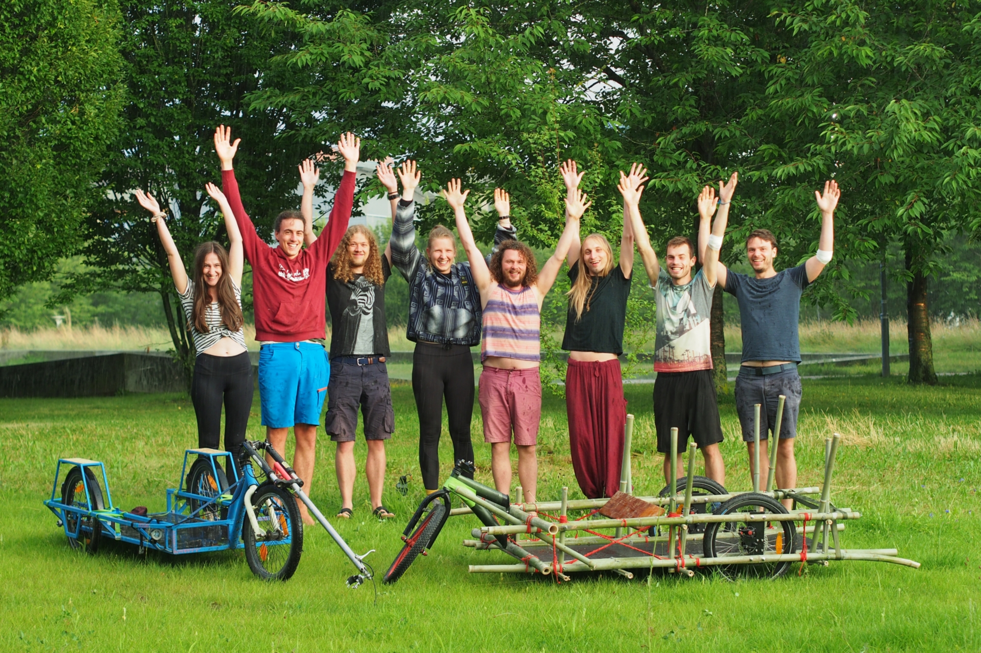 The project team: eight students stretching their arms upwards and standing behind two cargo bikes.