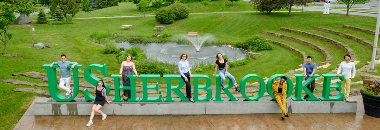 Étudiants sur le campus posant à travers les lettres géantes USHERBROOKE