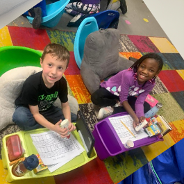 Boy and girl sitting on ground working on project