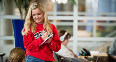 Student writing in notebook in the University Center