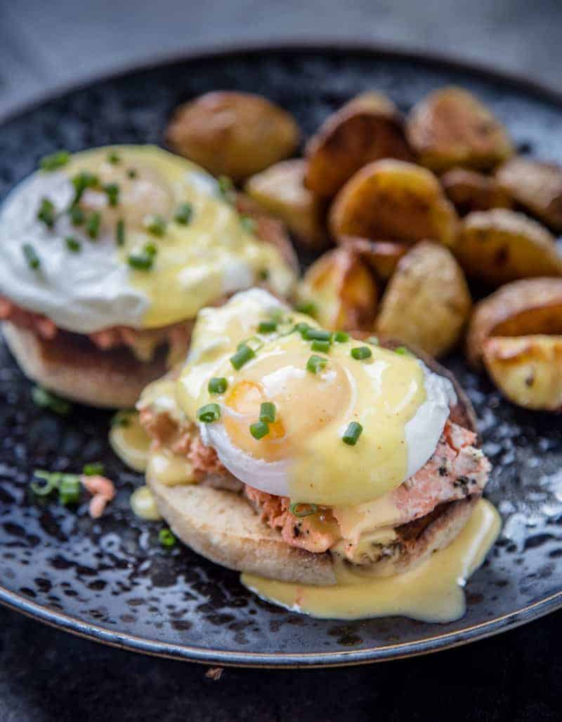 Smoked Salmon Eggs Benedict on a blue plate with roasted potatoes