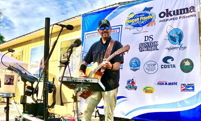 Musician Mike Cook with his guitar, performing at an outdoor venue