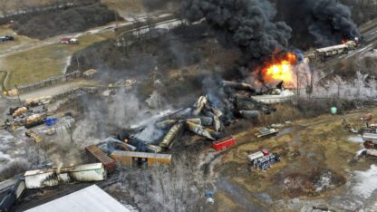 An overhead shot of several trains derailed and burning up in smoke.