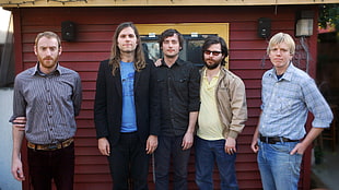 five men standing near red house at daytime