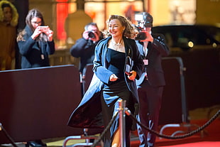 woman in black strapless dress with black coat walking on red carpet smiling