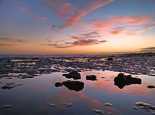 body of water surrounded by rocks under blue sky