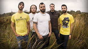 five men standing on grass field