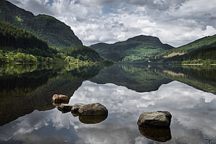 grey stones on calm clear water near mountains