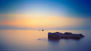 island on calm body of water under blue sky