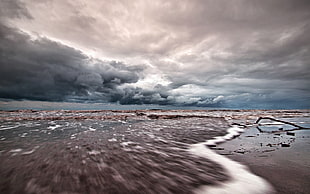 timelapse photography of seashore and ocean water under grey and white cloudy sky during daytime