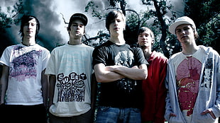 photography of five men standing front of trees