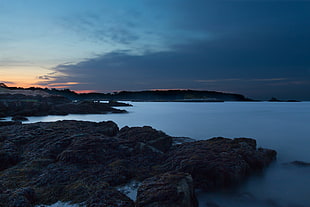 rock formation near body of water under blue skies