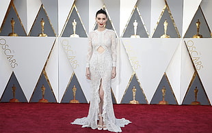 woman wears white long-sleeved floral dress on red carpet