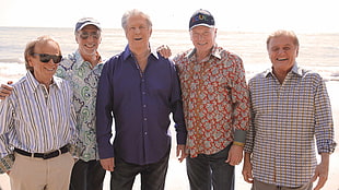 five men standing on beach shore during daytime