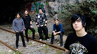 five persons sitting and standing on train track during daytime