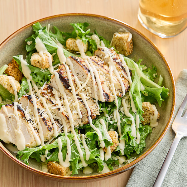 A salad with Ken's Caesar dressing, chicken, and croutons on a plate.