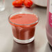 A glass cup with pink liquid next to a bottle of Ken's Foods Lite Raspberry Vinaigrette with a pink label.