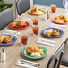 A table with Acopa Foundations melamine plates of food and drinks on it.