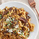 A plate of rice with dried porcini mushrooms and meat on a table.