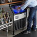 A man standing at a counter with a glass of ice.