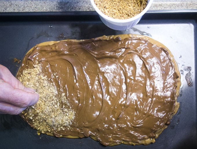 spreading almonds on buttercrunch with hands