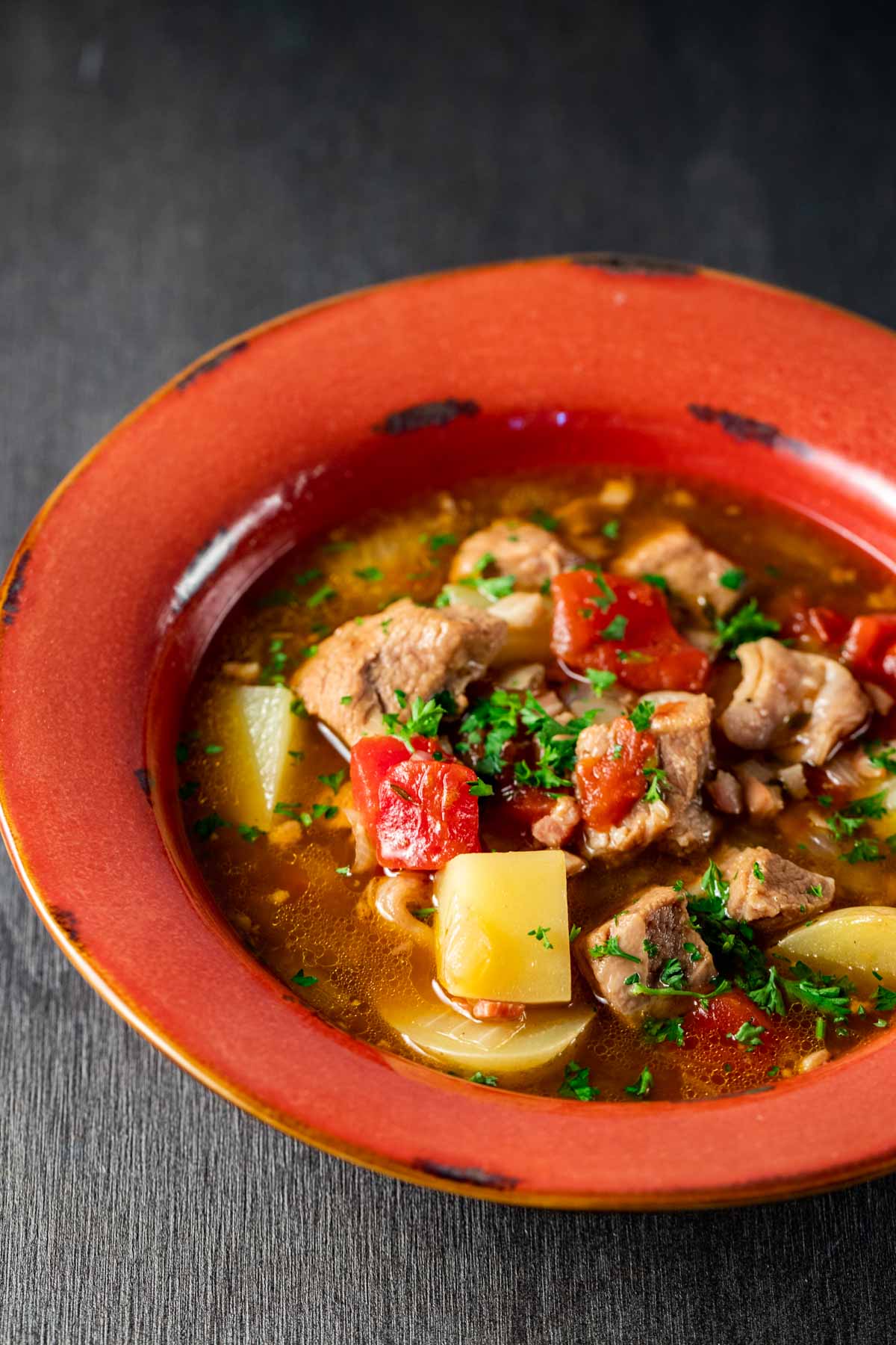 Veal stew served in a red bowl.