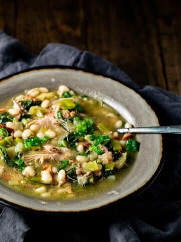 stew in a grey bowl with a metal spoon on a black or grey napkin