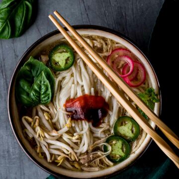 a bowl of vietnamese pho with condiments and chopsticks