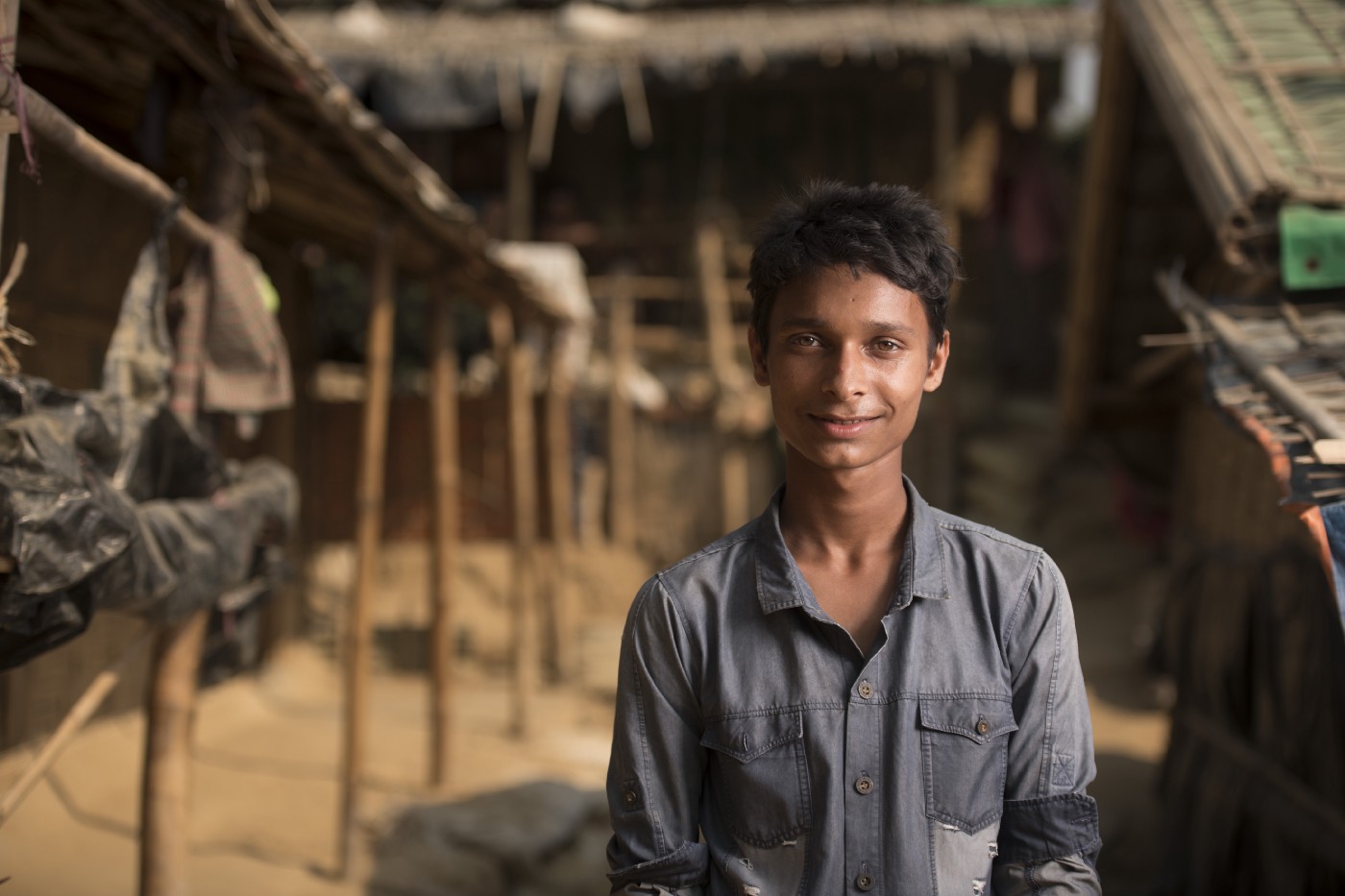 boy in grey button down stands outside house