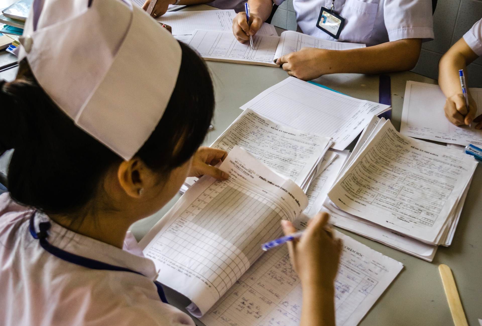 A nurse looks at some health data and completes tables.