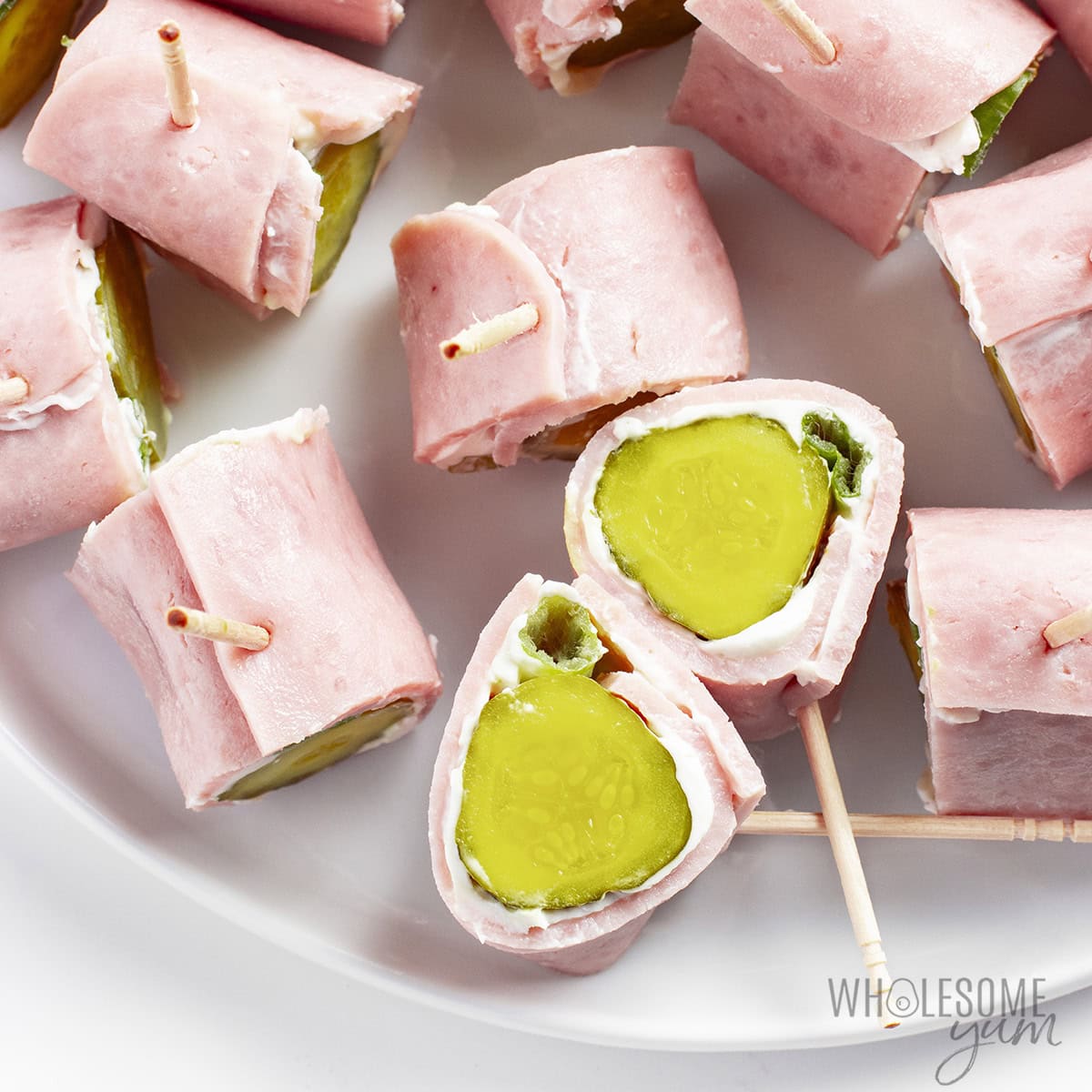 Finished ham pickle roll ups on a platter, secured with toothpicks.