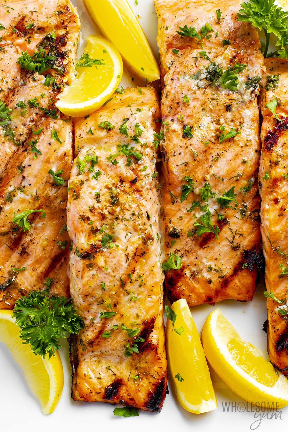 Tender, flaky grilled salmon with lemon wedges on a plate.