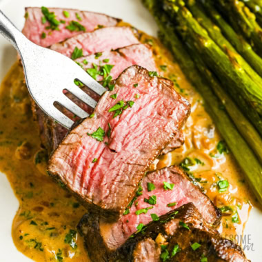 Steak Diane sliced on a plate with a fork.