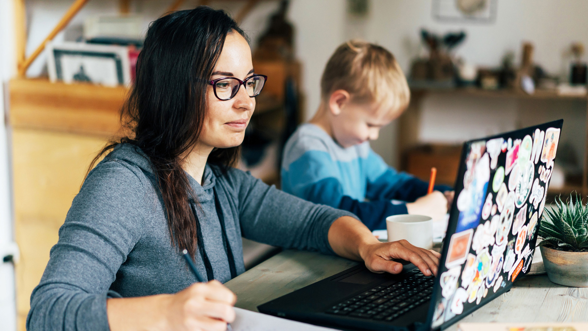 Adult student doing course work online while a child plays nearby