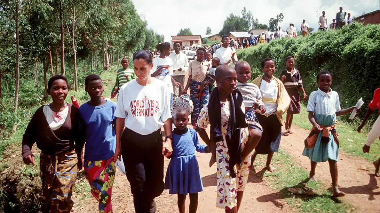 Bambino sorridente in Rwanda, seduto all'aperto su uno sfondo naturale, parte di un progetto di sostegno di World Vision.