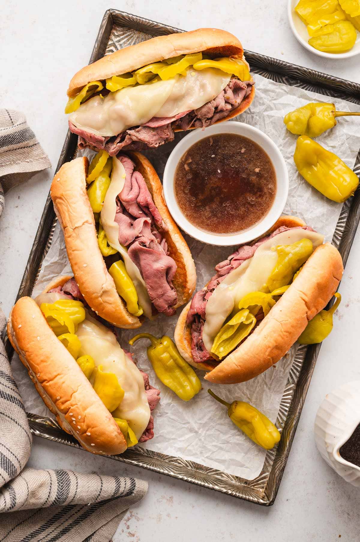 Italian beef sandwiches on hoagie rolls on a sheet pan.