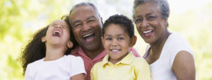 An elderly couple laughing with a young girl and boy.