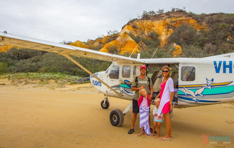 family standing beside plane on beach