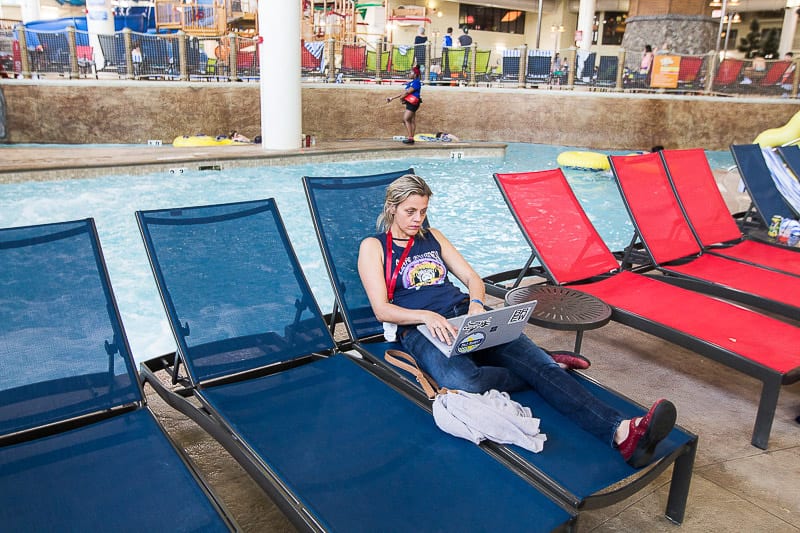 woman sitting by pool on computer