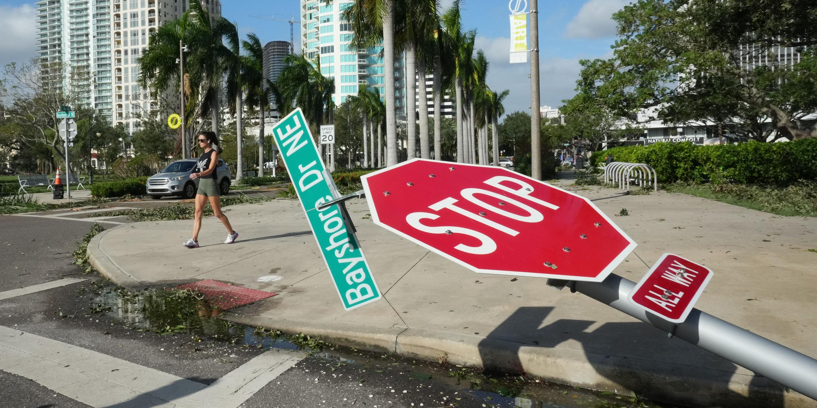 Anwohner gehen am 10. Oktober 2024 in Florida an einem umgestürzten Straßenschild entlang des Bayshore Drive in St. Petersburg vorbei, das durch den Hurrikan Milton verursacht wurde.