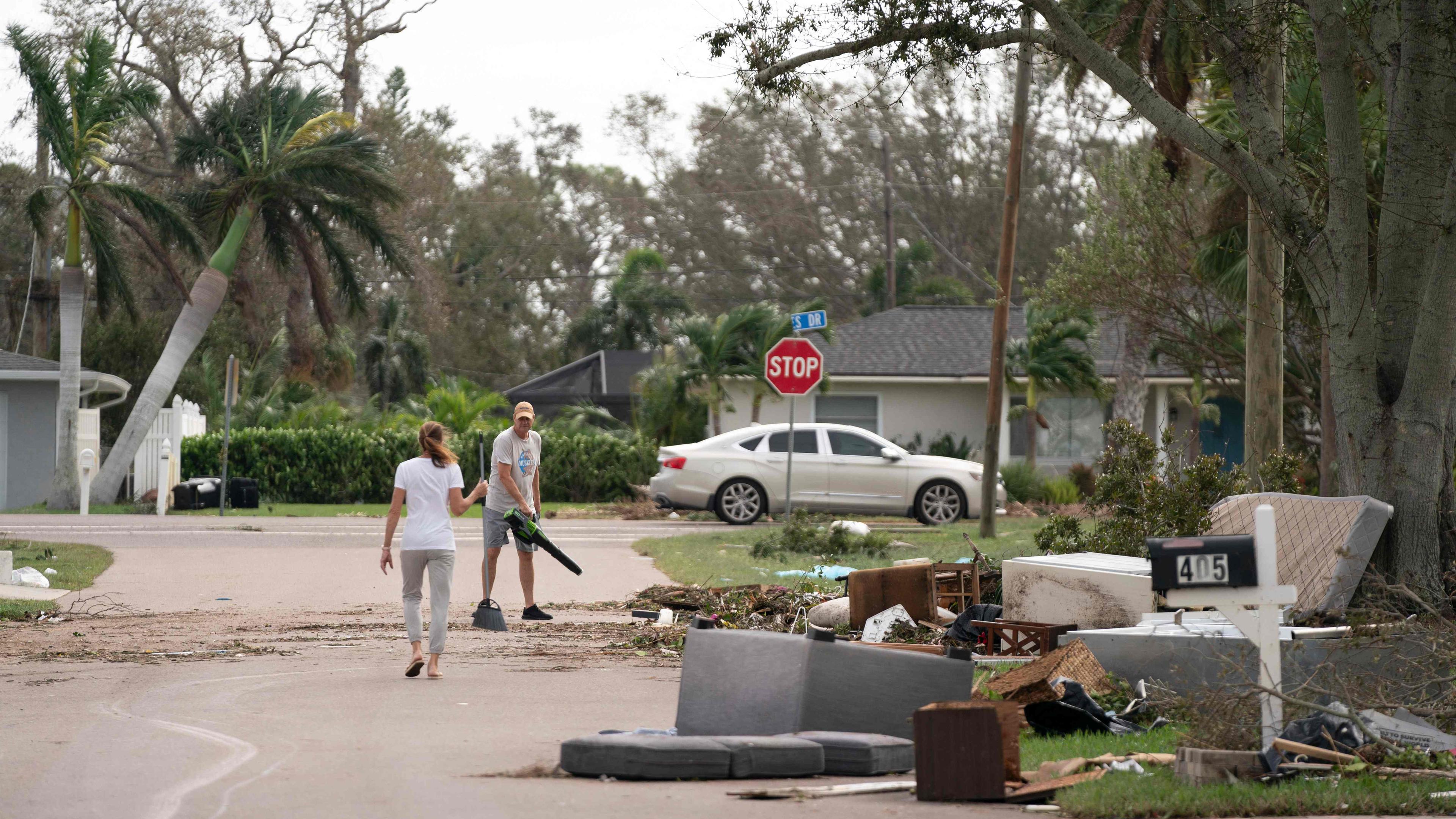 Anwohner säubern am 10. Oktober 2024 in Venice, Florida, eine Straße, die mit Sturmtrümmern von Hurrikan Helene und Hurrikan Milton übersät ist.