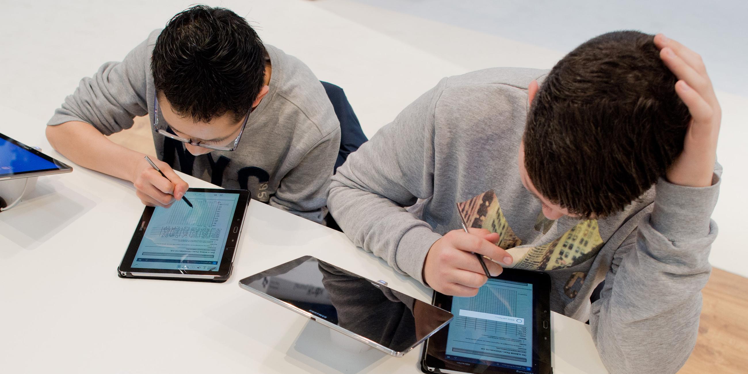 Zwei Schüler, welche mit ihren Tablets für die Schule lernen.