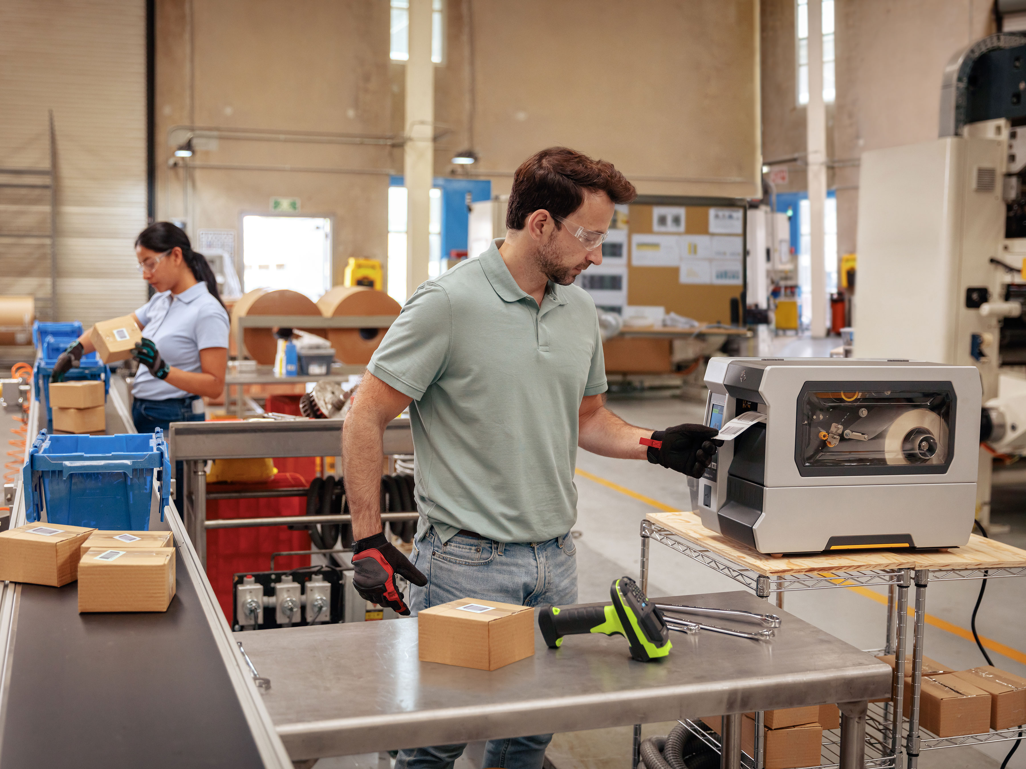 Zebra mobile printer attached to a belt strap prints labels and receipts in a warehouse while worker enters information on a handheld computer