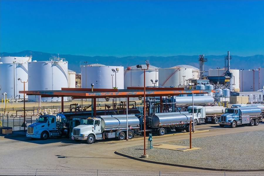 Trucks lined up outside storage tanks