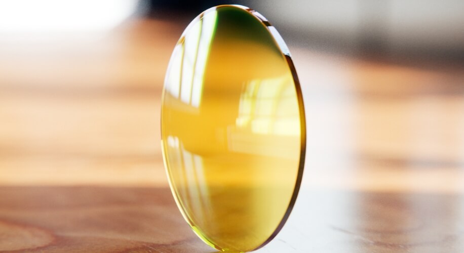 Yellow-tinted optical lens standing upright.